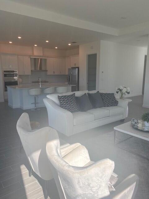 An open-concept living room features a white sofa, two armchairs, and a kitchen island — 1121 Haywagon Trail, Loxahatchee FL 33470, LOXAHATCHEE, FL