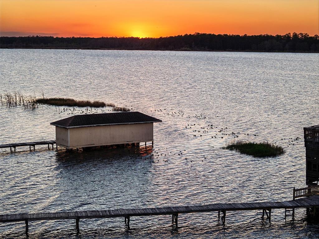 A boathouse sits on a lake at sunset with a wooden dock in the foreground — 14051 MARINE COURT, ORLANDO, FL