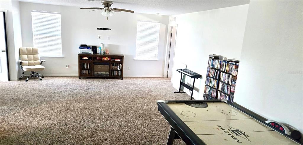 A carpeted room features an air hockey table, a media console, and a bookshelf — 1273 WATER WILLOW DRIVE, GROVELAND, FL
