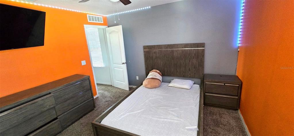 A bedroom features orange and gray walls, a wooden bed frame, and a matching dresser — 1273 WATER WILLOW DRIVE, GROVELAND, FL