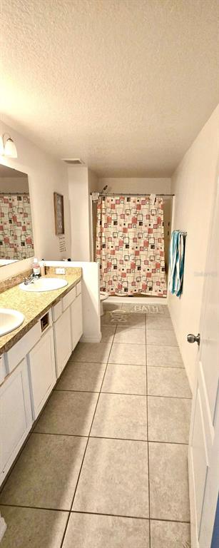 A bathroom features a double vanity with a granite countertop, tile flooring, and a shower curtain — 1273 WATER WILLOW DRIVE, GROVELAND, FL