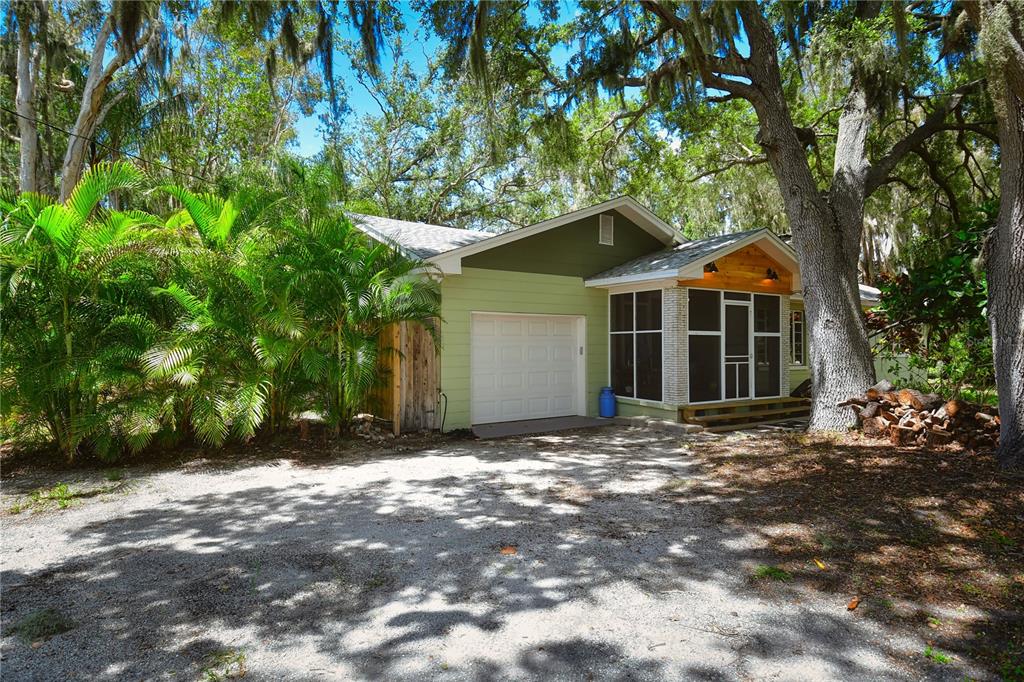 A light green house with a garage and a screened-in porch sits among large trees — 160 BAYSHORE DRIVE, TERRA CEIA, FL