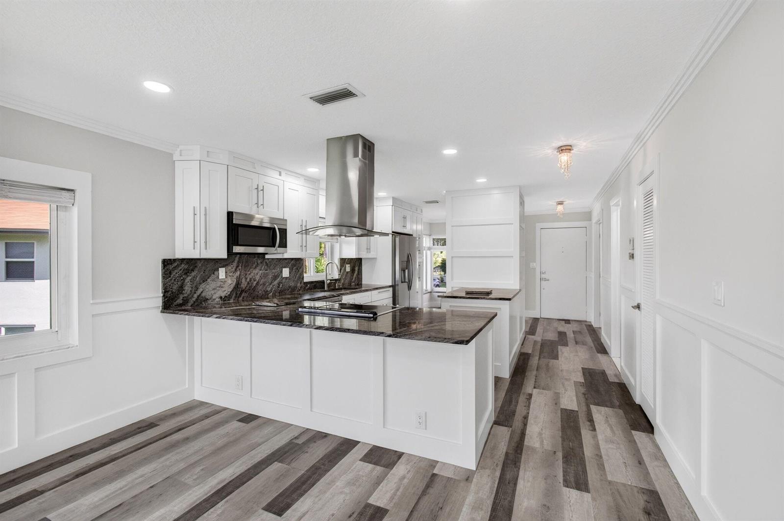 A kitchen with white cabinets, dark granite countertops, a stainless steel hood, and wood flooring — 5650 Spindle Palm Court # D, Delray Beach FL 33484, DELRAY BEACH, FL