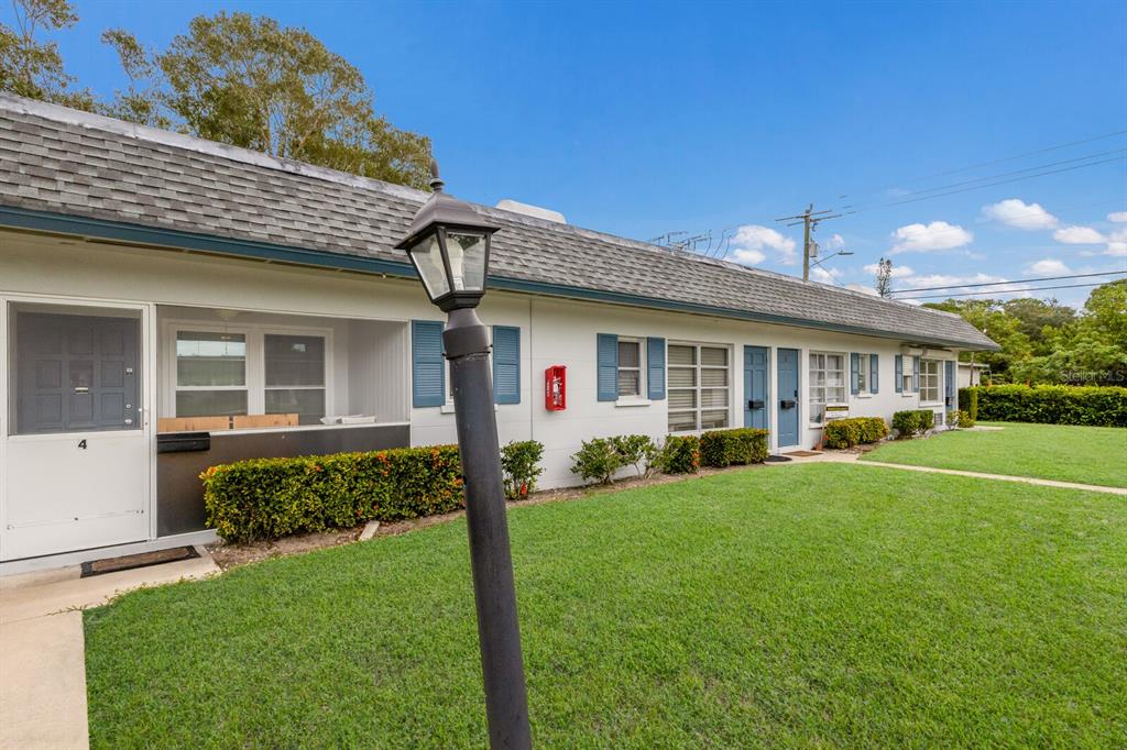 A single-story apartment building with white siding, blue shutters, and a grassy front lawn — 4444 SWIFT ROAD UNIT 4, SARASOTA, FL