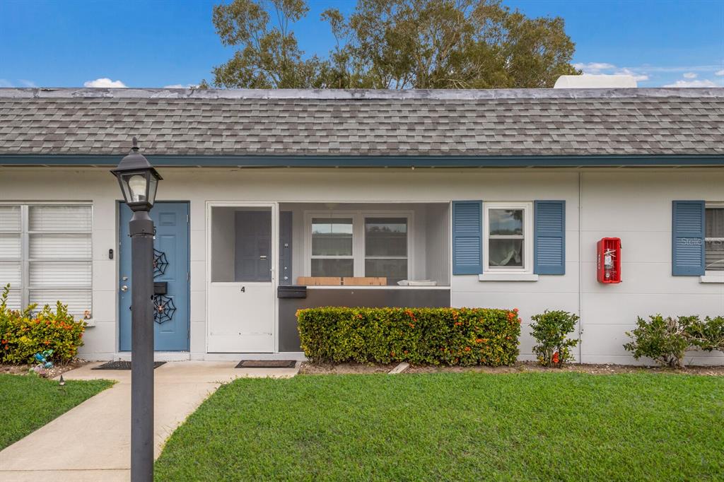 A single-story residential unit with a blue door, screened porch, and a red fire extinguisher — 4444 SWIFT ROAD UNIT 4, SARASOTA, FL