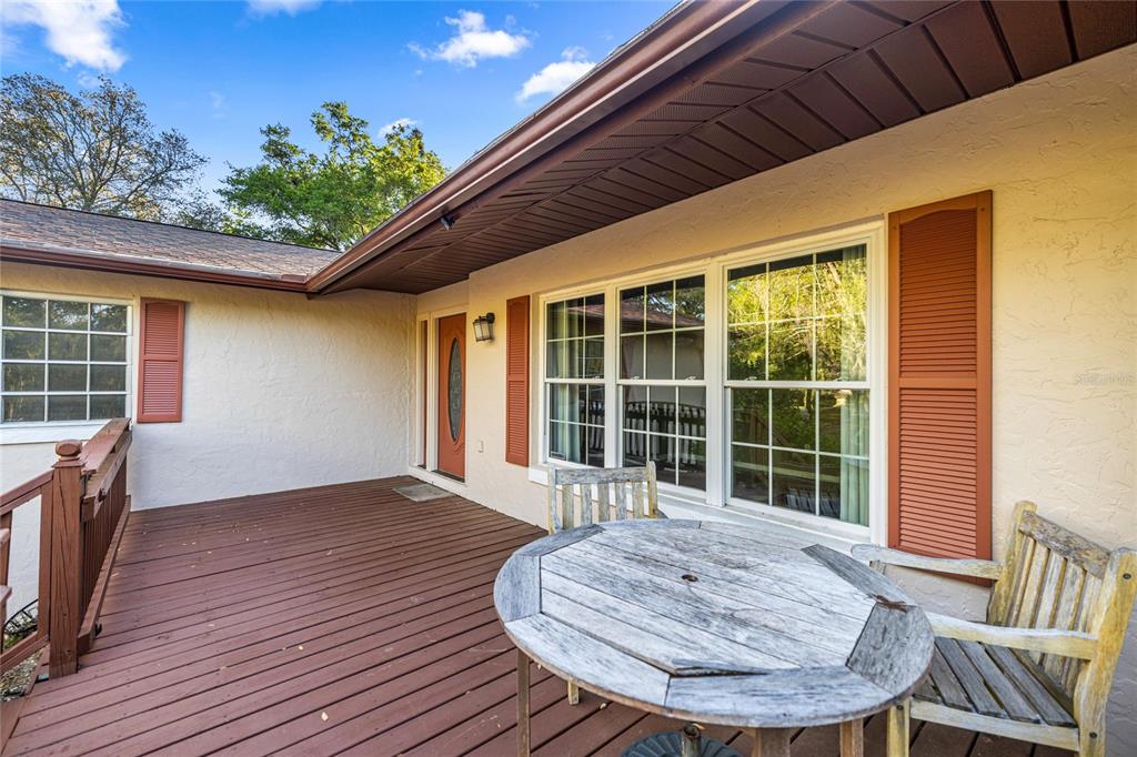 A wooden deck features a weathered round table and chair in front of a house — 20949 SW 81ST LOOP, DUNNELLON, FL