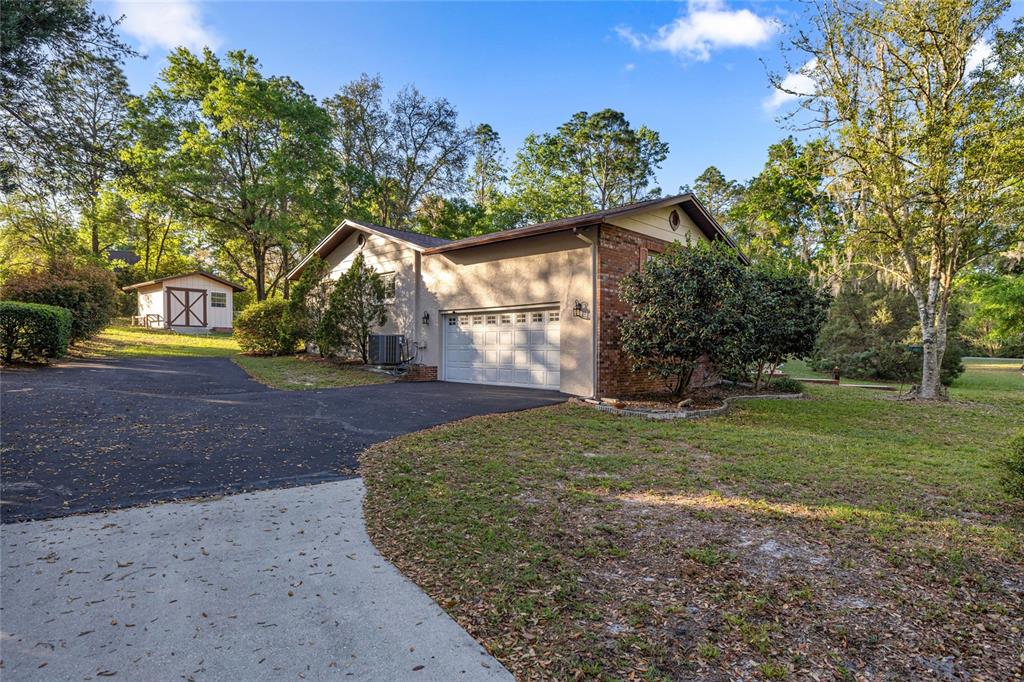A single-story house with a brick and stucco exterior, a garage, and a detached shed — 20949 SW 81ST LOOP, DUNNELLON, FL