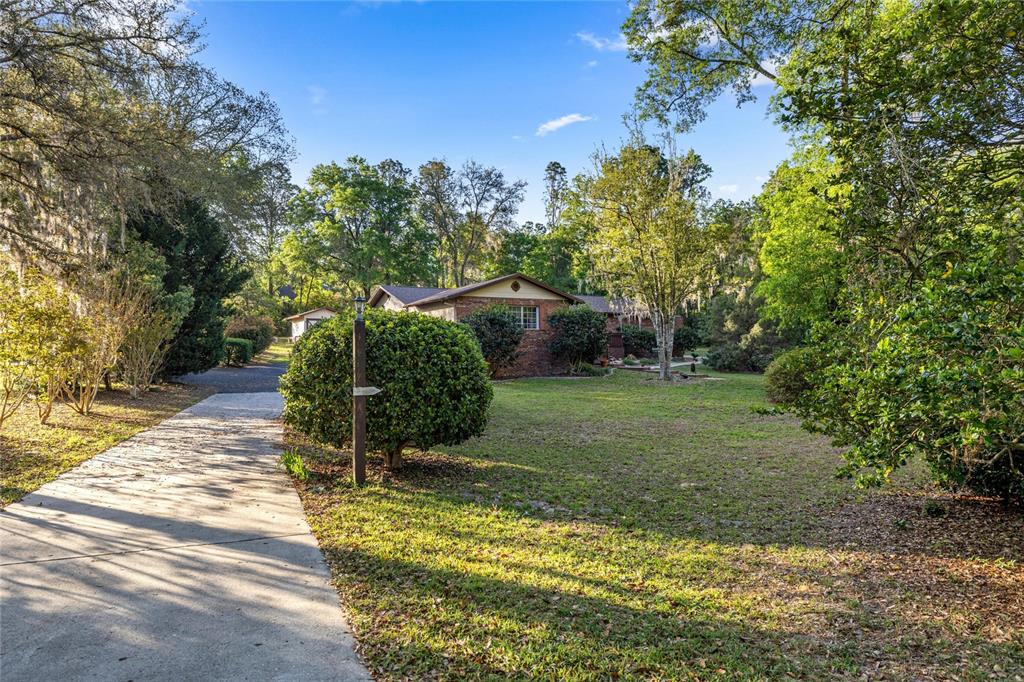 A brick house sits at the end of a concrete driveway surrounded by mature trees — 20949 SW 81ST LOOP, DUNNELLON, FL