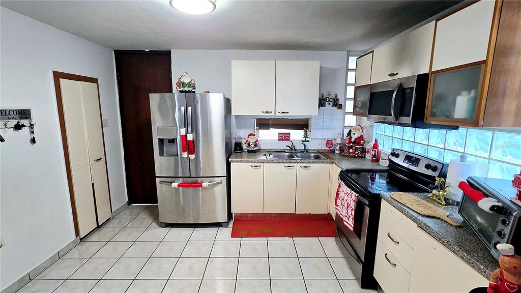 A kitchen features white cabinets, stainless steel appliances, a tiled floor, and holiday decorations — Italia URB. PLAZA DE LA FUENTE UNIT 1010, TOA ALTA, PR