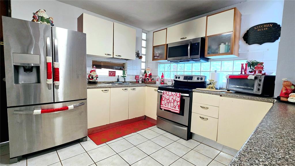 A kitchen features stainless steel appliances, off-white cabinets, a tiled floor, and holiday decorations — Italia URB. PLAZA DE LA FUENTE UNIT 1010, TOA ALTA, PR