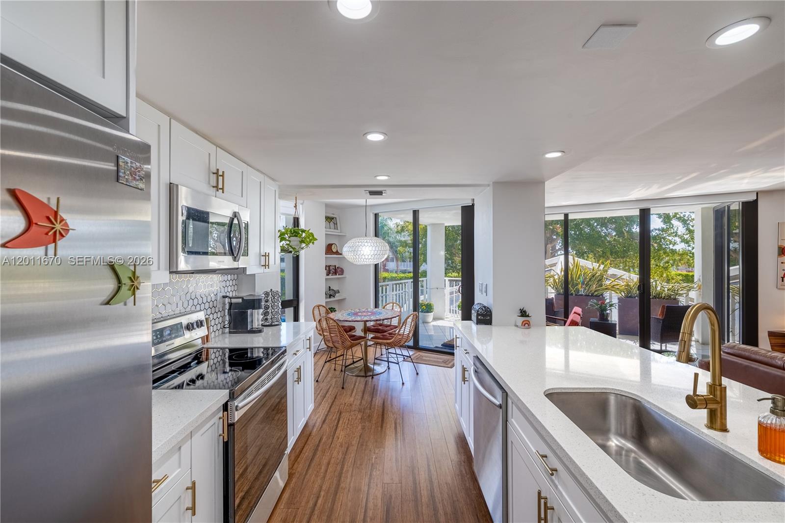 A modern kitchen features white cabinets, quartz countertops, stainless steel appliances, and a dining area — 4000 Towerside Ter # 308, Miami FL 33138, MIAMI, FL