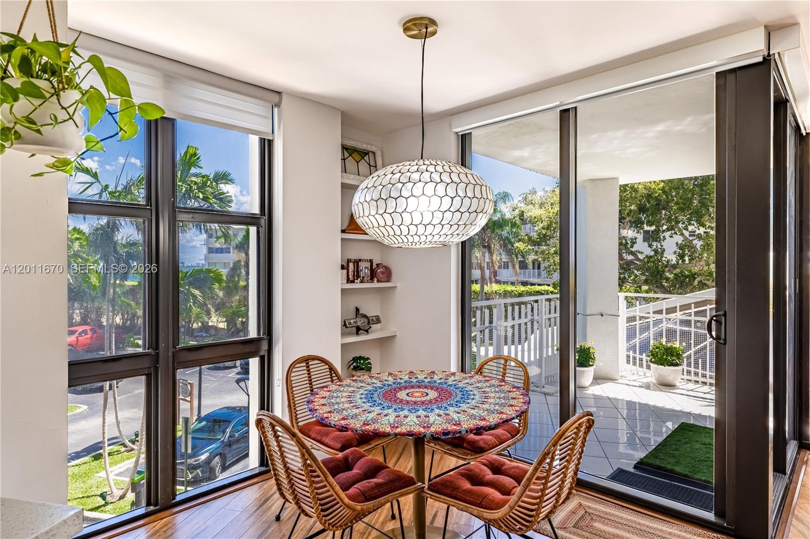 A dining area features a round patterned table, rattan chairs, and large windows overlooking outdoors — 4000 Towerside Ter # 308, Miami FL 33138, MIAMI, FL
