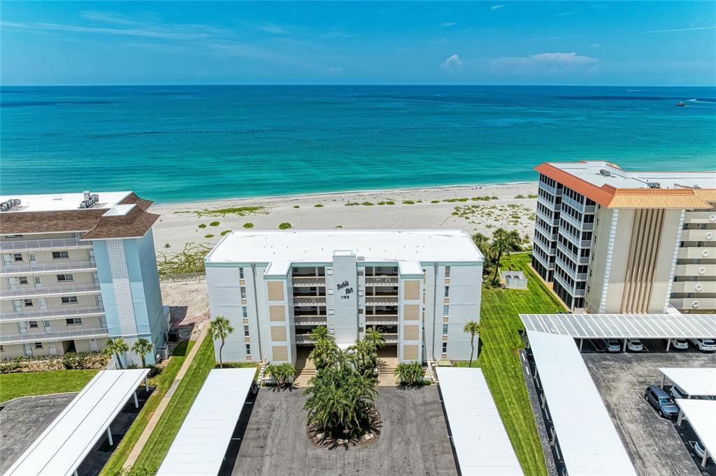 An aerial view of a beachfront condominium complex with parking carports and a sandy beach — 1100 TARPON CENTER DRIVE UNIT 104, VENICE, FL