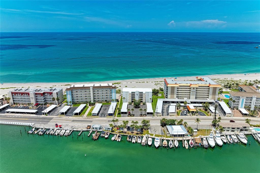 An aerial view shows beachfront condominiums with covered parking and a boat dock — 1100 TARPON CENTER DRIVE UNIT 104, VENICE, FL