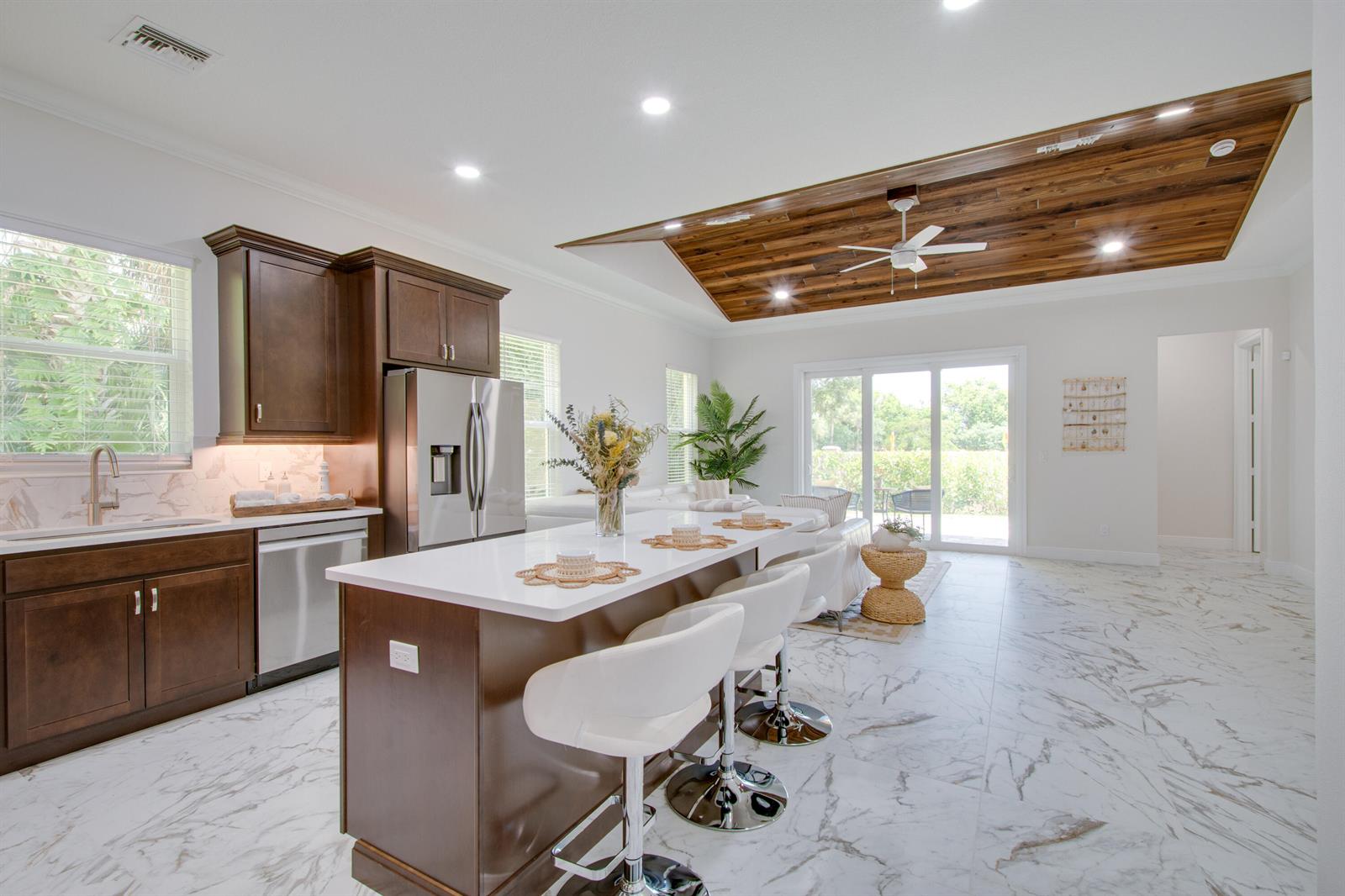 A kitchen with dark wood cabinets, a white island, and a wood-paneled tray ceiling — 1805 Bridgepointe Circle # 1, Vero Beach FL 32967, VERO BEACH, FL