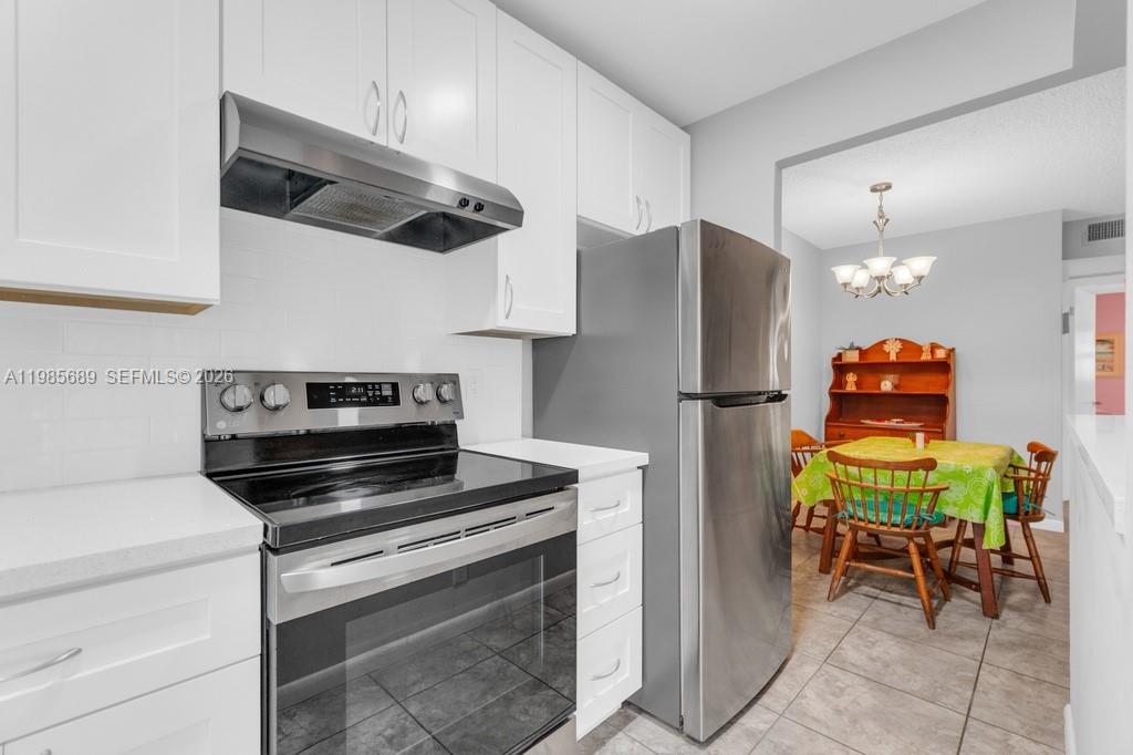 A kitchen with white cabinets, stainless steel appliances, and an adjacent dining area — 5300 Washington St # J218, Hollywood FL 33021, HOLLYWOOD, FL