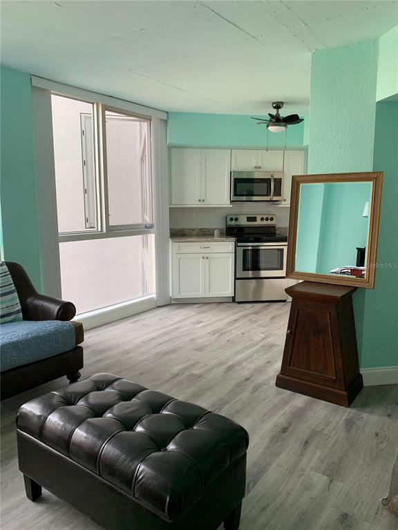 A kitchen with white cabinets and stainless steel appliances sits next to a living area — 470 3RD STREET S UNIT 616, ST PETERSBURG, FL
