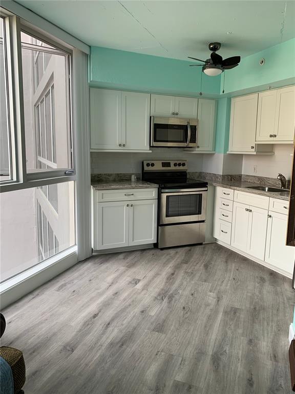 A kitchen with white cabinets, stainless steel appliances, and light wood-look flooring — 470 3RD STREET S UNIT 616, ST PETERSBURG, FL