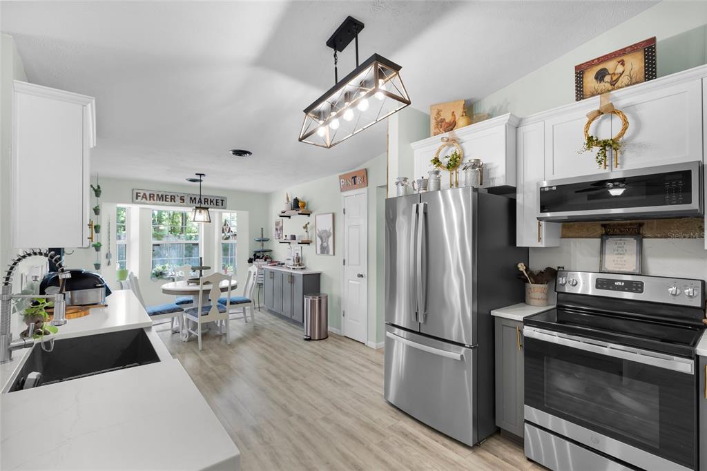 An open-concept living room and kitchen featuring light wood flooring and a fireplace — 4630 SE 58TH PLACE, OCALA, FL