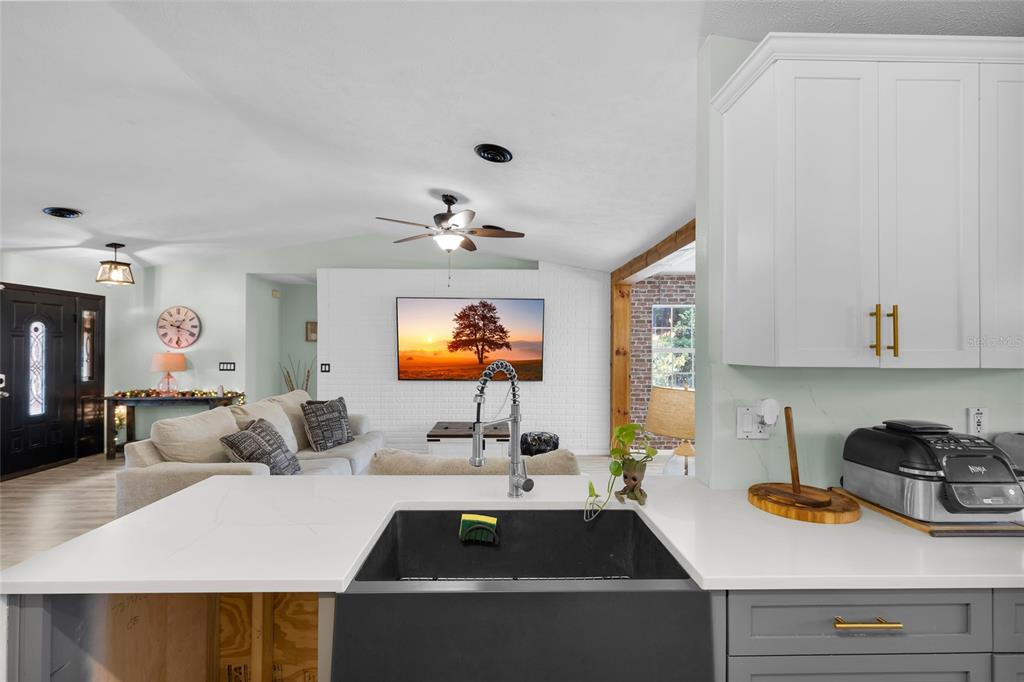 A modern kitchen features white upper cabinets, gray lower cabinets, stainless steel appliances, and wood-look flooring — 4630 SE 58TH PLACE, OCALA, FL