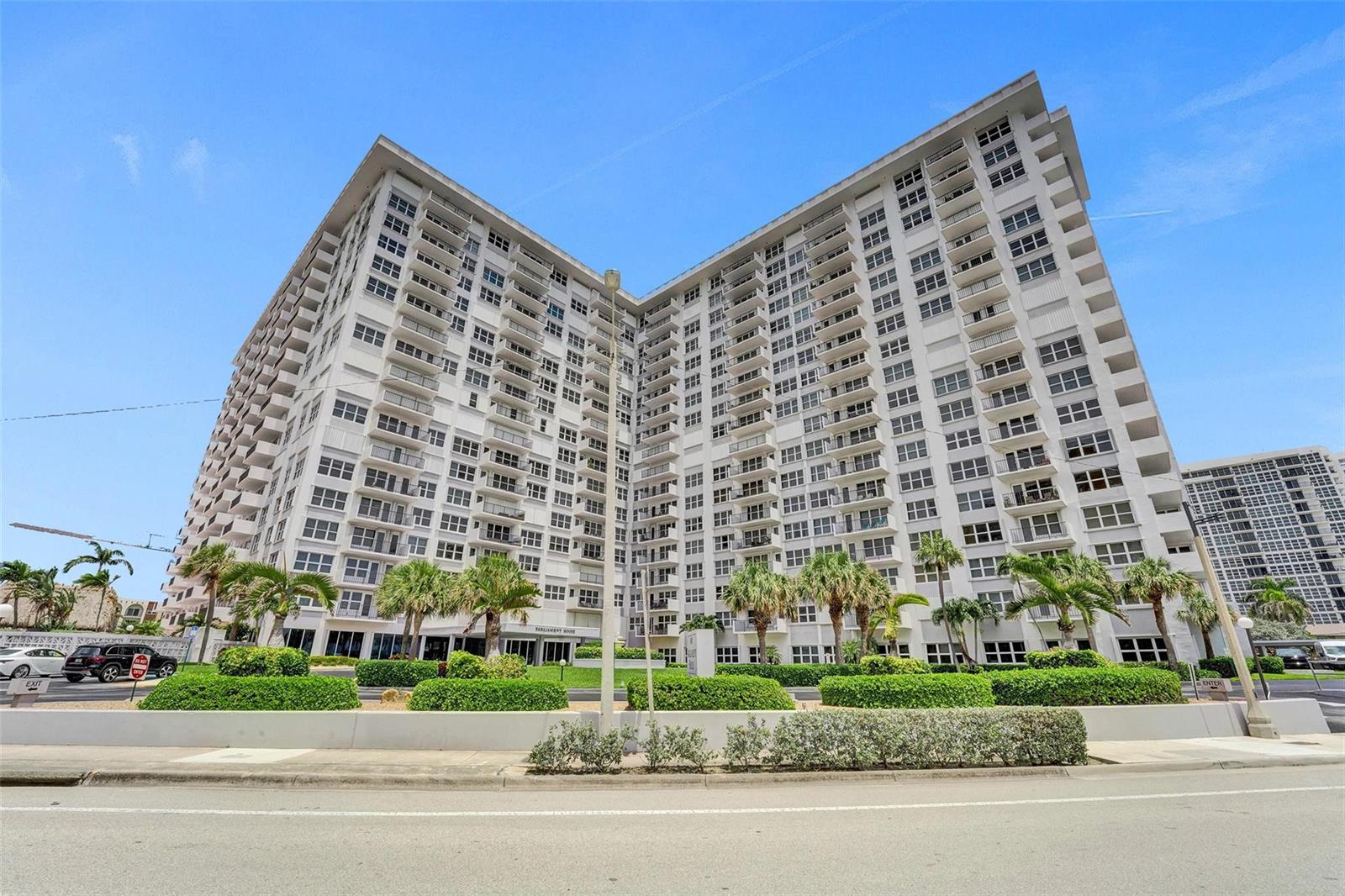 A tall, white multi-story apartment building stands behind a landscaped lawn with palm trees — 405 N Ocean Boulevard # 623, Pompano Beach FL 33062, POMPANO BEACH, FL