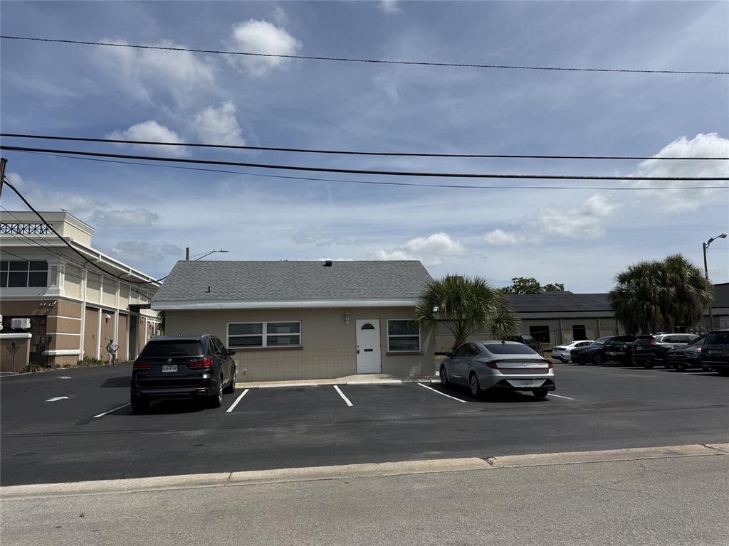 A single-story tan building with a gray roof sits behind a paved parking lot — 1240 ROGERS STREET, CLEARWATER, FL