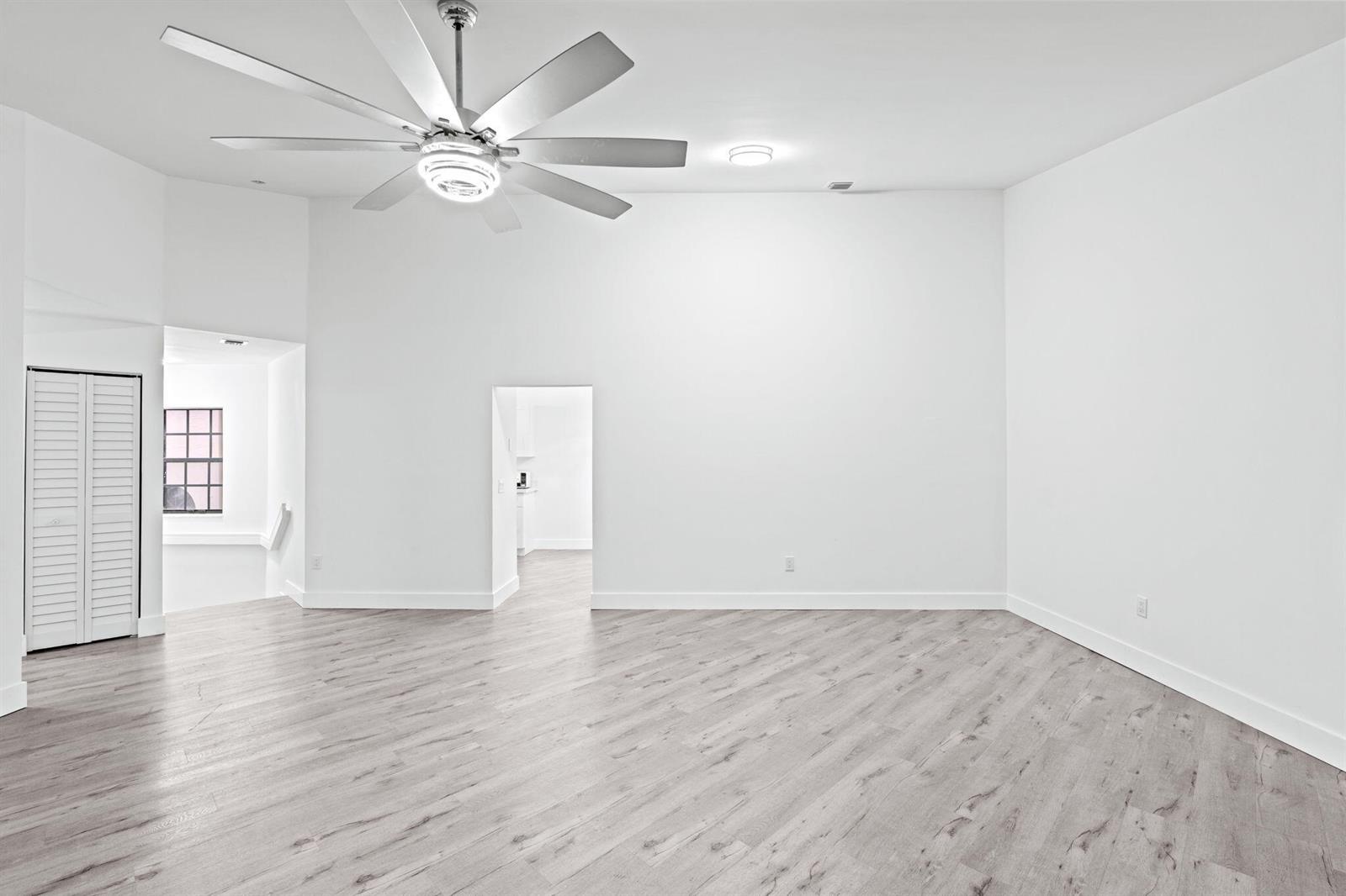 An empty room with light wood-look flooring, white walls, and a large ceiling fan — 5131 Europa Drive # I, Boynton Beach FL 33437, BOYNTON BEACH, FL