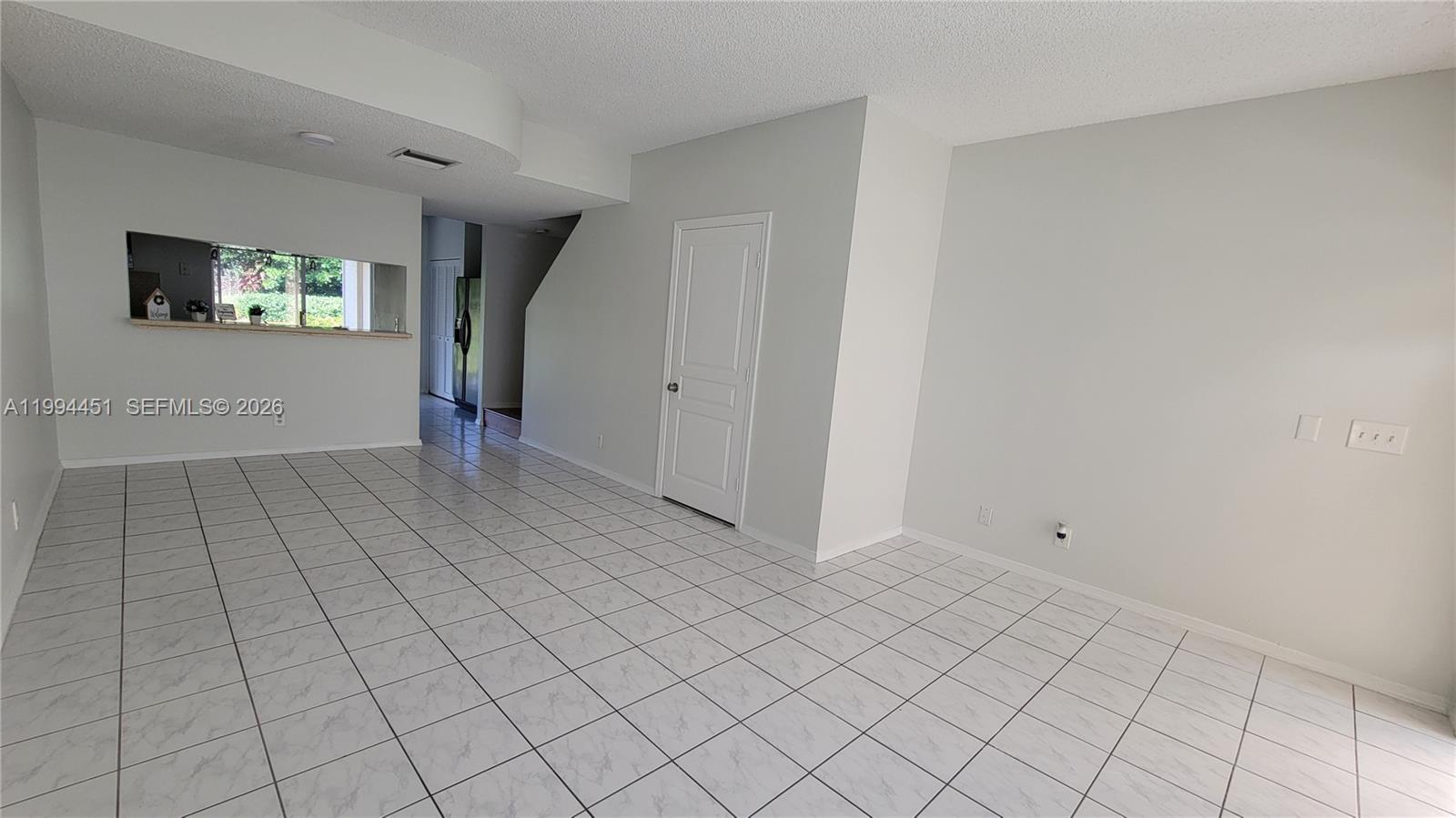 A tiled room features a pass-through window to the kitchen and a white door — 16731 Hemingway Dr, Weston FL 33326, WESTON, FL