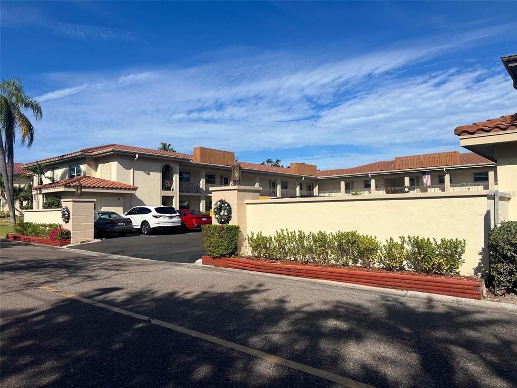 An exterior view of a two-story apartment complex with a parking lot and perimeter wall — 19029 US HIGHWAY 19 N UNIT 6-14, CLEARWATER, FL
