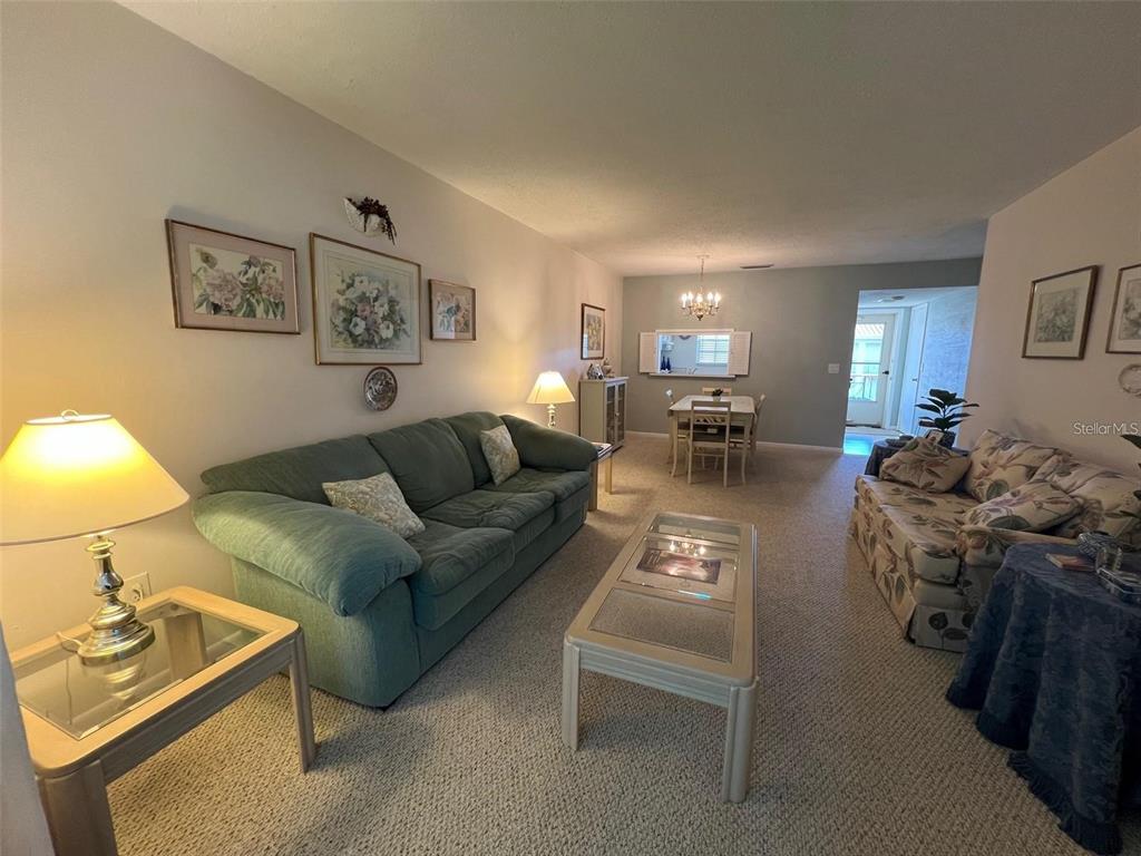 A living room with a green sofa, floral loveseat, coffee table, and adjacent dining area — 19029 US HIGHWAY 19 N UNIT 6-14, CLEARWATER, FL