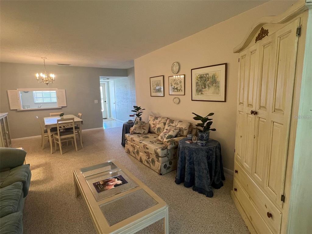 A living room features a floral sofa, a glass-top coffee table, and a tall cabinet — 19029 US HIGHWAY 19 N UNIT 6-14, CLEARWATER, FL