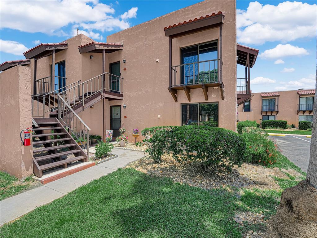 A two-story stucco apartment building features an exterior wooden staircase and a small balcony — 121 LA CASA UNIT 5, LAKE WALES, FL