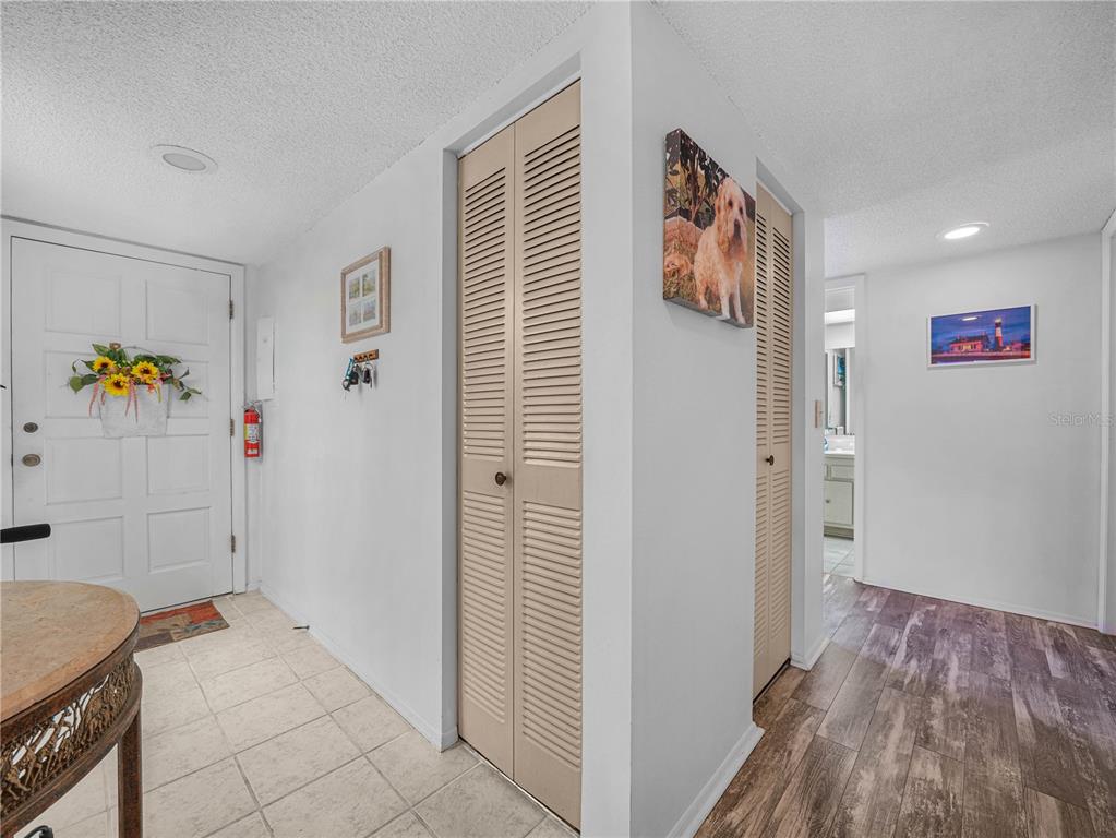 An entryway features a white door, louvered closet doors, and a mix of tile and wood flooring — 121 LA CASA UNIT 5, LAKE WALES, FL