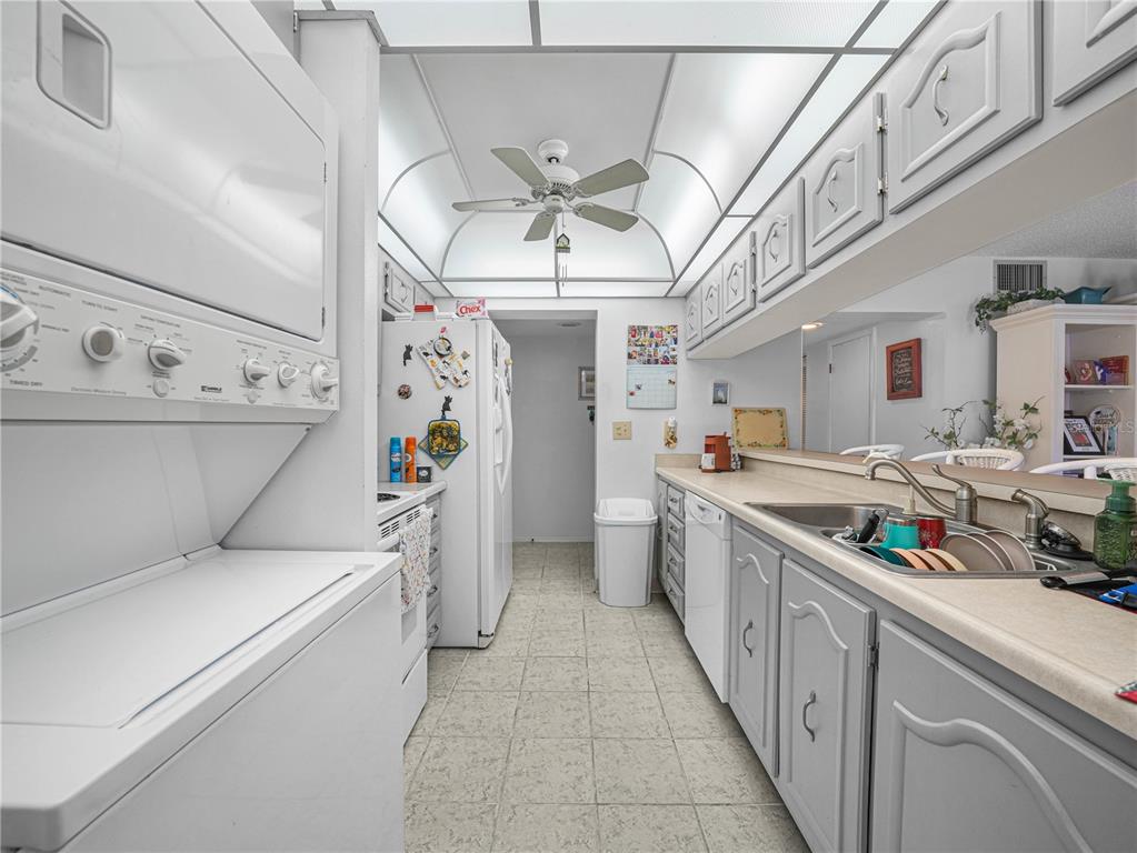 A kitchen features white cabinets, a stacked washer-dryer unit, and a stainless steel sink — 121 LA CASA UNIT 5, LAKE WALES, FL