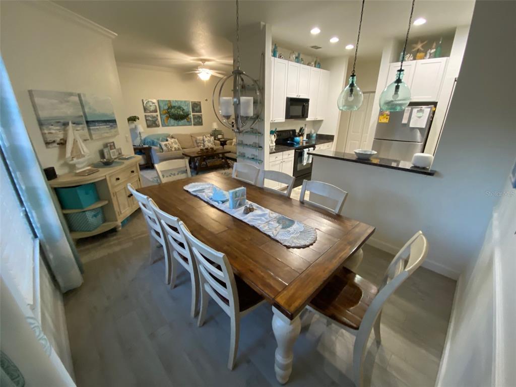 A dining room with a wooden table and chairs opens into a kitchen and living area — 2107 PORTOFINO PLACE UNIT 3011, PALM HARBOR, FL