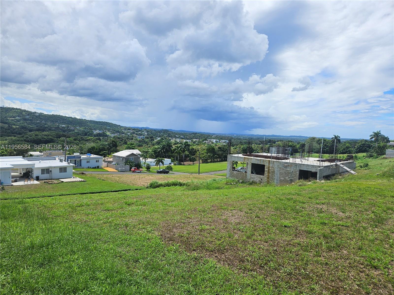 An elevated view shows a grassy lot with a partially constructed concrete building nearby — URB MIRADOR DE PALMER . SOLAR 41 RIO GRANDE, PR 00745, PR