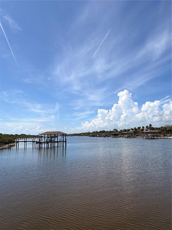A view of a calm waterway with multiple wooden boat docks under a blue sky — 2691 SUNSET INLE DRIVE, FLAGLER BEACH, FL