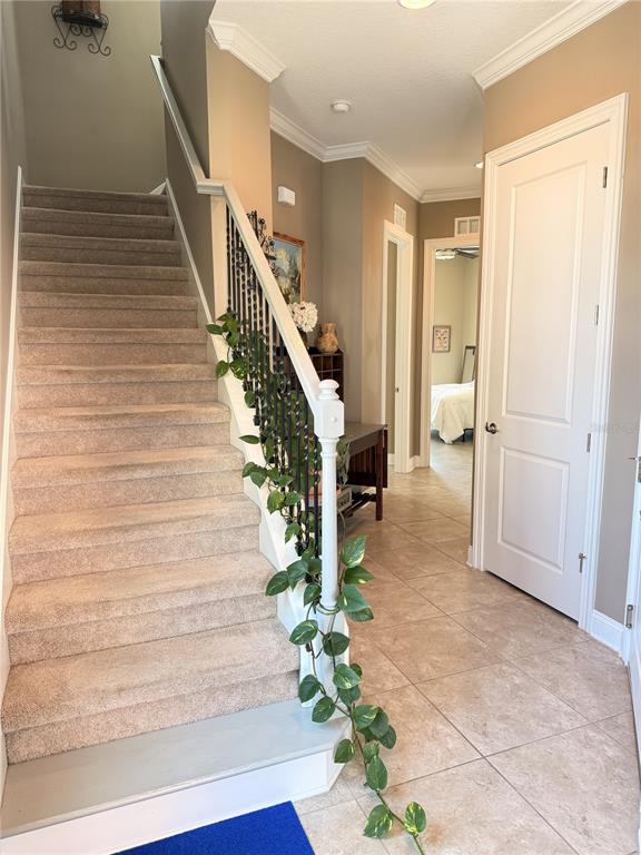 A carpeted staircase with a decorative railing leads to an upper level in a tiled foyer — 2691 SUNSET INLE DRIVE, FLAGLER BEACH, FL