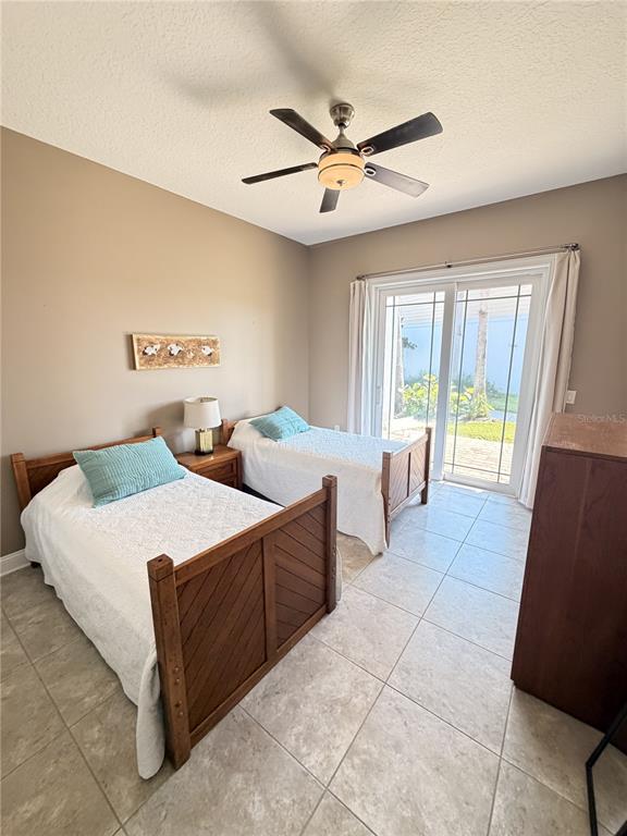 A bedroom features two twin beds, tile flooring, a ceiling fan, and sliding glass doors — 2691 SUNSET INLE DRIVE, FLAGLER BEACH, FL