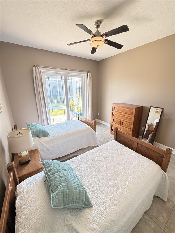 A bedroom with two twin beds, a wooden dresser, a floor mirror, and sliding glass doors — 2691 SUNSET INLE DRIVE, FLAGLER BEACH, FL