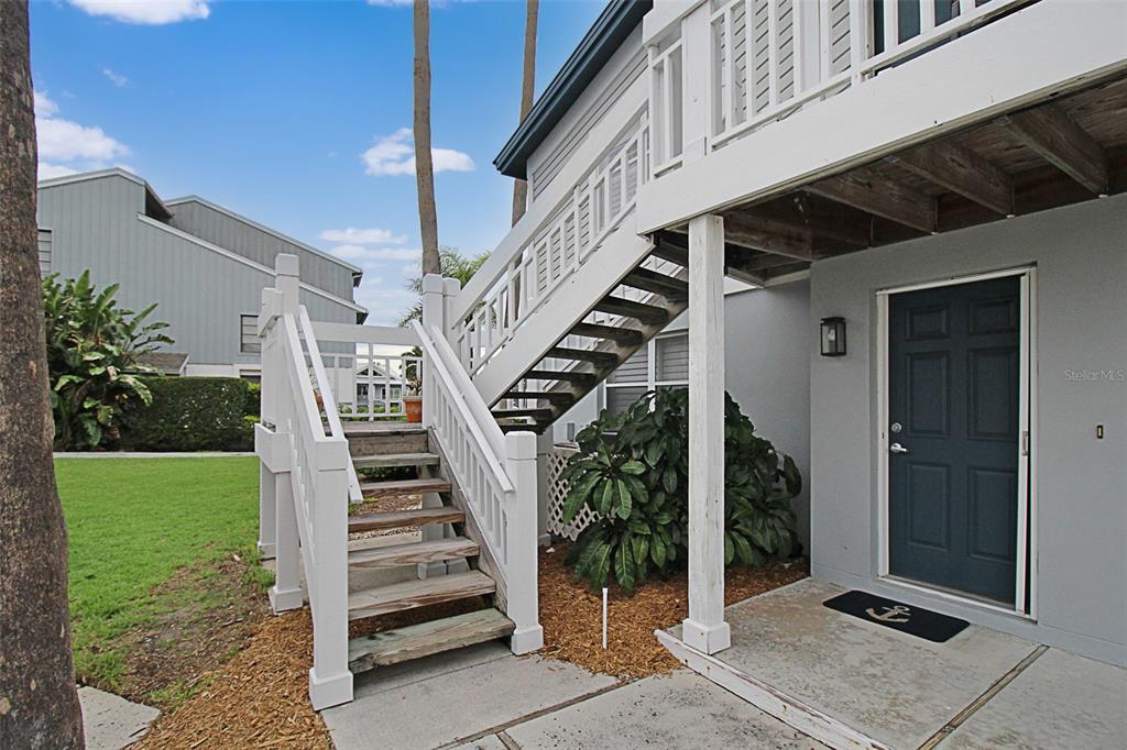 An exterior view of a building with a wooden staircase leading to an upper deck — 1339 SIESTA BAYSIDE DRIVE UNIT 1339-C, SARASOTA, FL