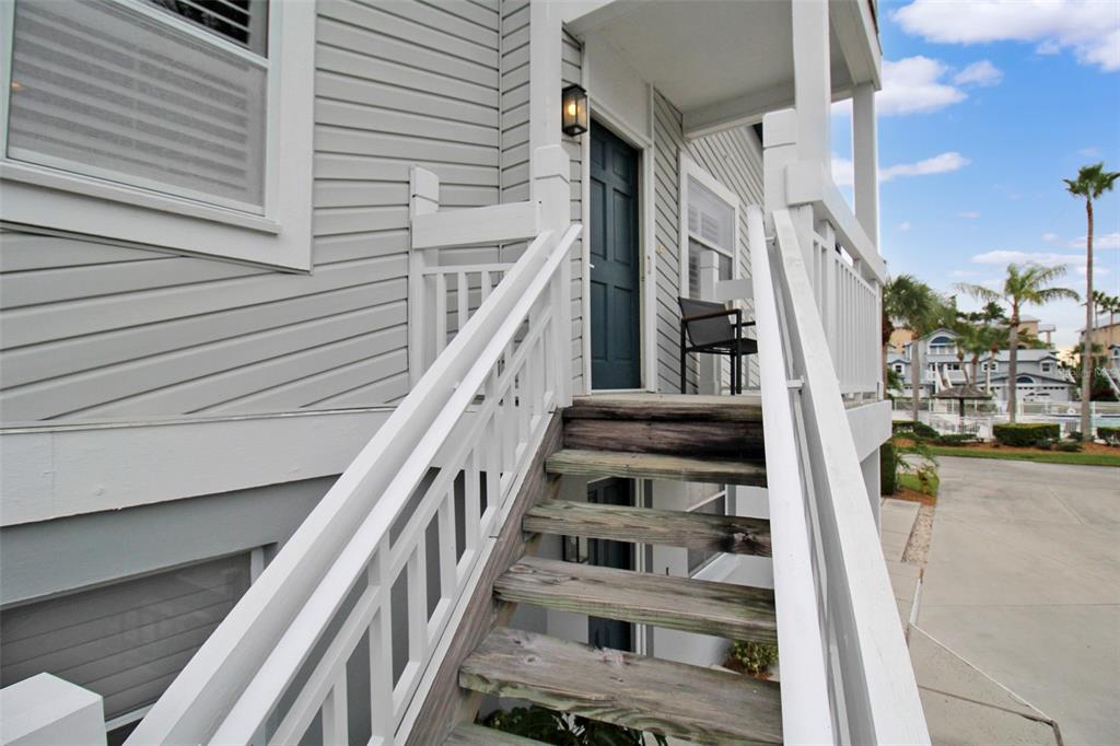 An exterior view of a wooden staircase leading to a raised porch with a dark door — 1339 SIESTA BAYSIDE DRIVE UNIT 1339-C, SARASOTA, FL