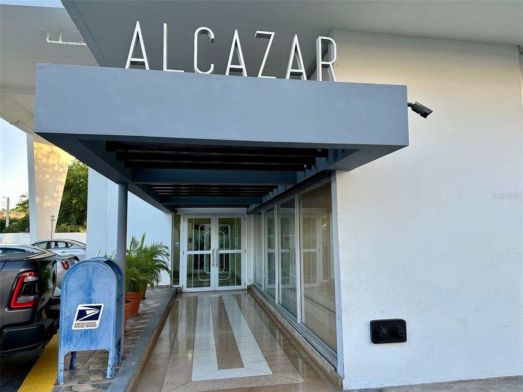 The exterior entrance of the Alcazar building features a covered walkway and a blue mailbox — 1802 ALCAZAR UNIT 404, PONCE, PR