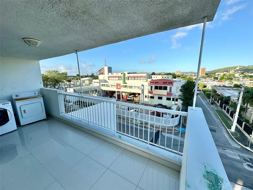A balcony with tile flooring, a washer and dryer, and a view of a building — 1802 ALCAZAR UNIT 404, PONCE, PR