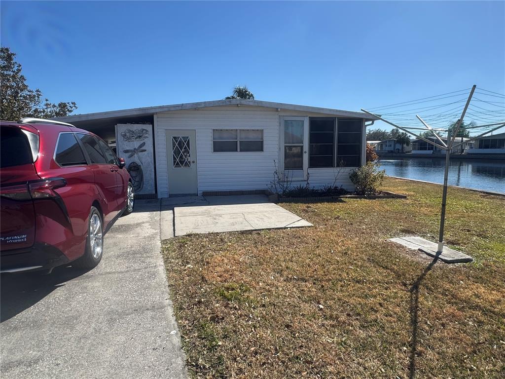 A single-story mobile home with a red minivan parked on a concrete driveway — 4842 BRITNI WAY UNIT 058, ZEPHYRHILLS, FL