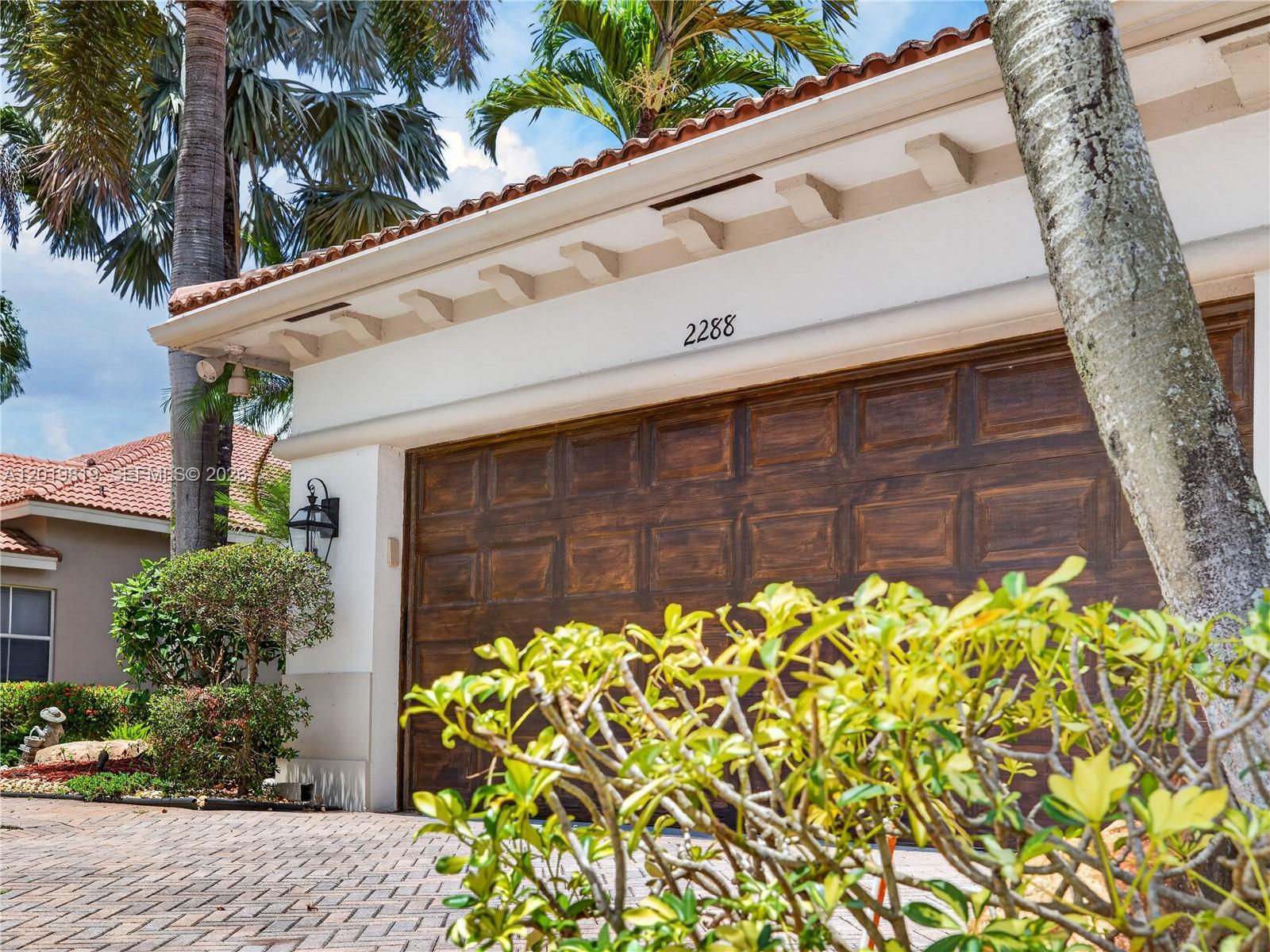 A brown garage door with a house number is set into a white stucco exterior — 2288 Quail Roost Dr, Weston FL 33327, WESTON, FL
