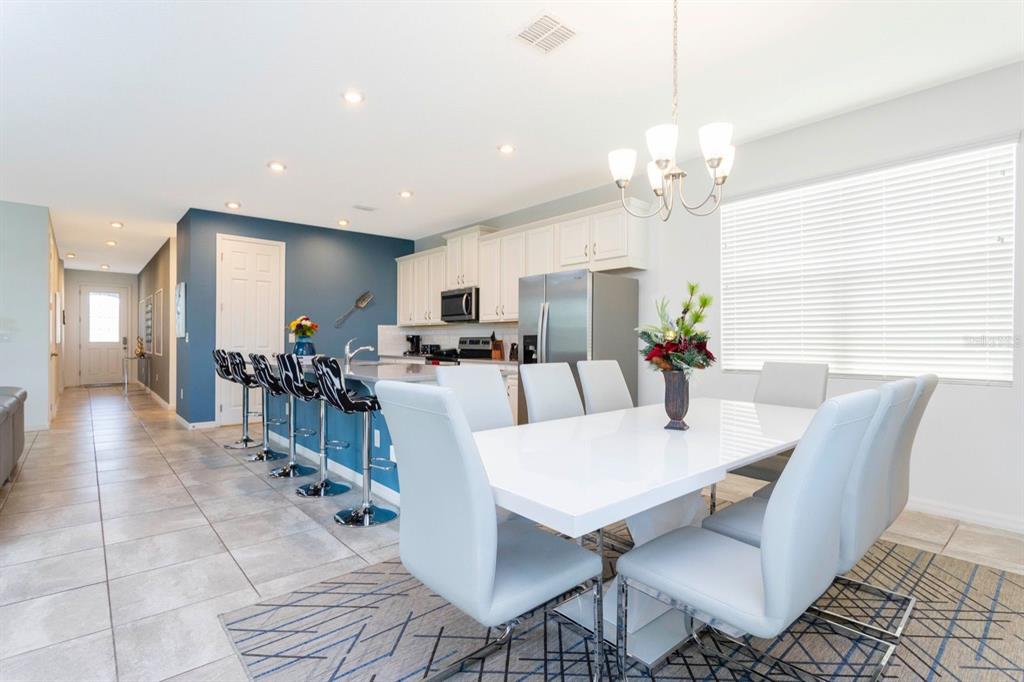 A dining area and kitchen with white cabinets, a blue accent wall, and tiled floors — 8995 AMELIA DOWNS TRAIL, KISSIMMEE, FL