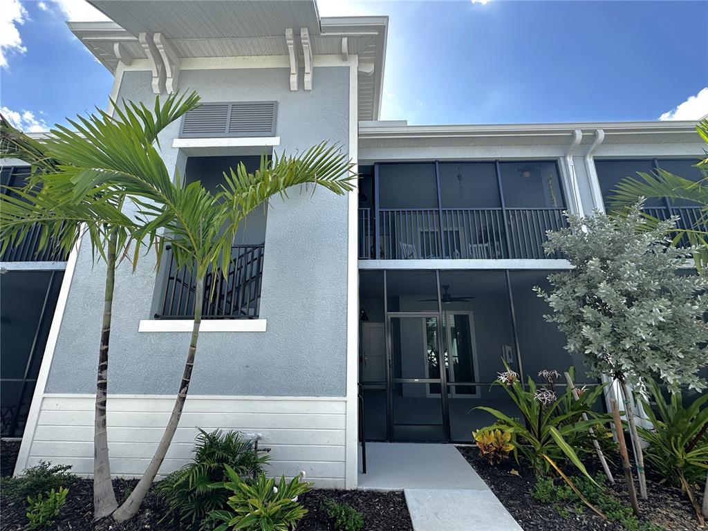A two-story building exterior features a screened-in patio, a balcony, and palm trees — 14267 HERITAGE LANDING BOULEVARD UNIT 1222, PUNTA GORDA, FL