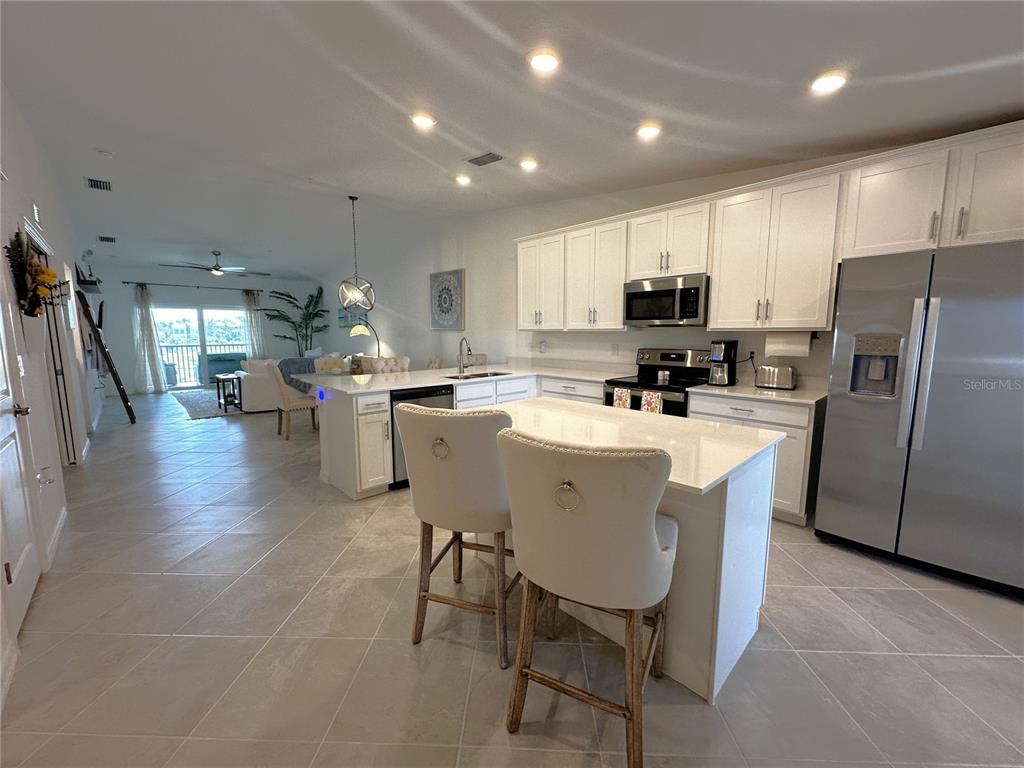 A kitchen with white cabinets, stainless steel appliances, and an island with two bar stools — 14267 HERITAGE LANDING BOULEVARD UNIT 1222, PUNTA GORDA, FL