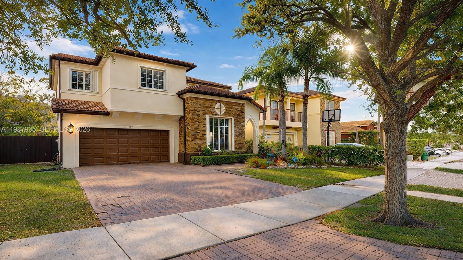 A two-story house with a stone facade, brown garage door, and a brick driveway — 16479 SW 50th Ter, Miami FL 33185, MIAMI, FL